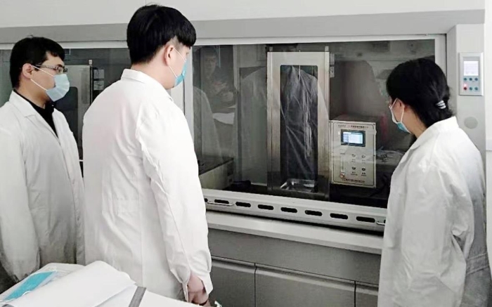 圖為吉林器械所檢驗(yàn)人員開展疫情防護(hù)用品的阻燃試驗(yàn)。