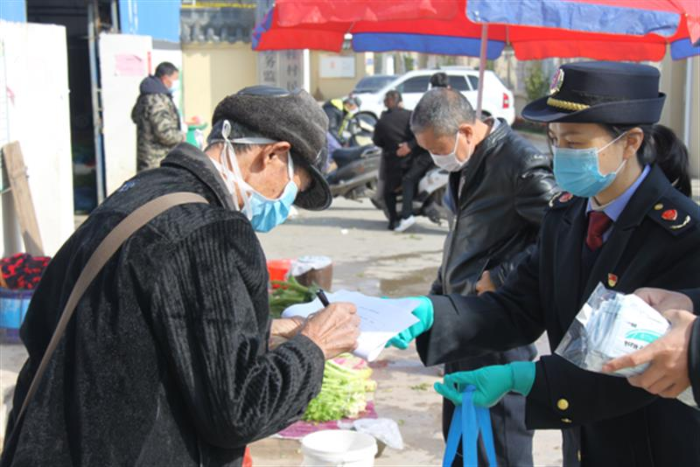 圖為鷹潭市市場監(jiān)管局工作人員向經(jīng)營戶發(fā)放口罩。