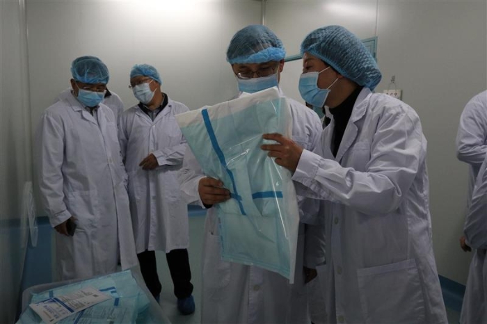 圖為云南省藥監(jiān)局黨組書記、局長劉本軍（右二）檢查該企業(yè)生產(chǎn)的醫(yī)用一次性防護(hù)服。（云南省藥監(jiān)局供圖）