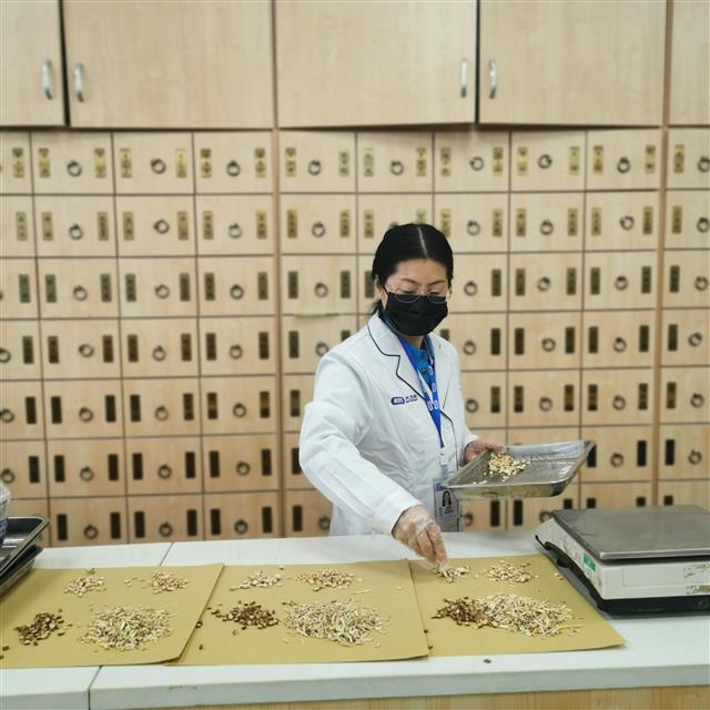 　侯惠鳴為顧客抓藥。