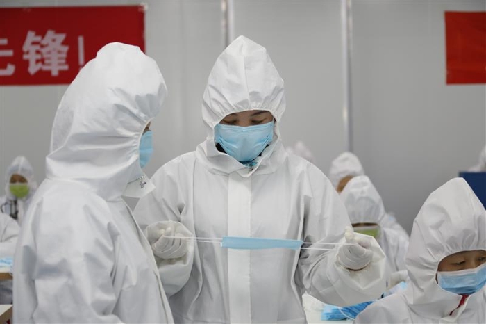 新疆維吾爾自治區(qū)藥監(jiān)局駐企特派員馬小華（右）正在與企業(yè)質(zhì)量負責人溝通口罩生產(chǎn)中遇到的問題。（馬少賓 攝）