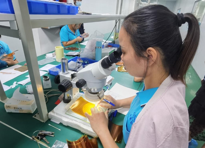 開蒙醫(yī)療員工在用顯微鏡檢查人體成分分析儀芯片上的箔片集成電路是否有缺陷。