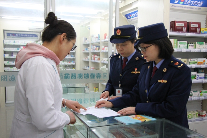 圖為執(zhí)法人員在佰藥之家大藥房發(fā)放安全用藥科普手冊。