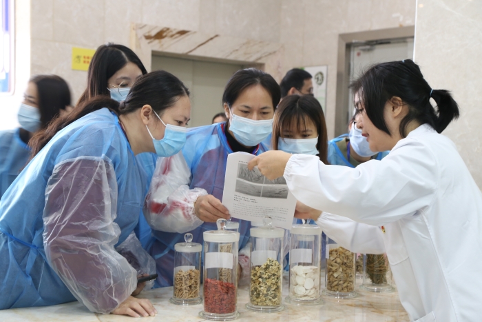 圖為工作人員為市民代表講解中藥材真?zhèn)舞b別知識。