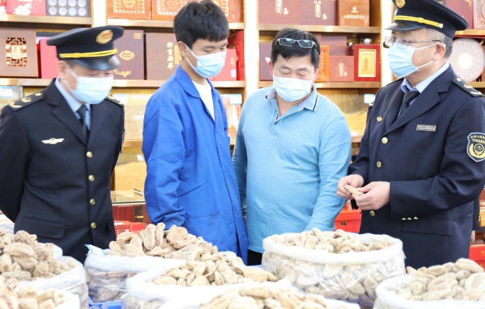 秦繼紅（右一）在中藥材市場門店查看。（喻燦華 攝）