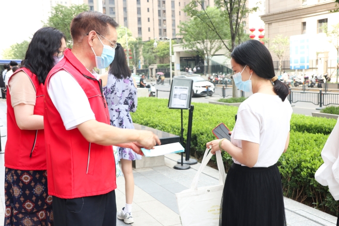 圖為藥監(jiān)系統(tǒng)志愿者為排隊(duì)等待檢測的居民發(fā)放科普抗疫小禮包，并為居民開展藥品安全科普，耐心解答居民用藥、用械安全方面的疑問和咨詢。（郝曉靜攝）