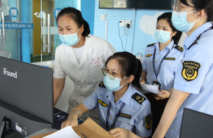 圖為鐘山縣市場監(jiān)管局執(zhí)法人員在一家疫苗接種單位檢查相關資質文件。