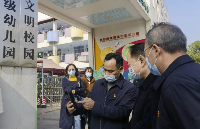 圖為樂運(yùn)成（右二）通過手機(jī)客戶端查看大通湖區(qū)第一實(shí)驗(yàn)幼兒園廚房實(shí)時(shí)視頻。