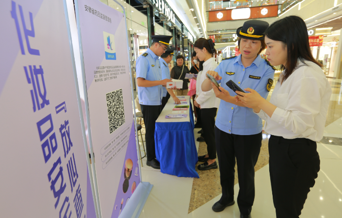 圖為9月13日，該局執(zhí)法人員正在指導(dǎo)化妝品經(jīng)營者安裝使用該APP。
