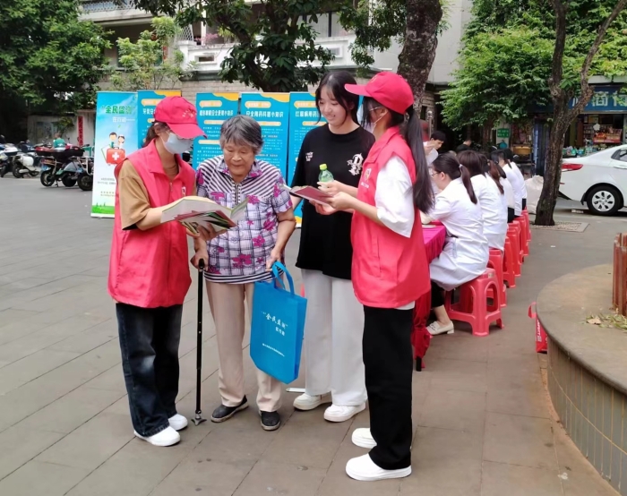 圖為工作人員向過往居民發(fā)放“全民監(jiān)測”科普宣傳資料。