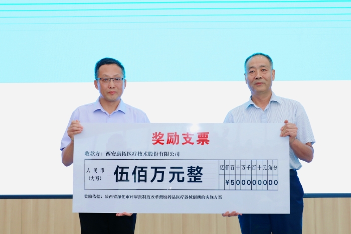 圖為研討會現(xiàn)場，陜西省藥監(jiān)局二級巡視員王志宏向西安康拓醫(yī)療技術(shù)股份有限公司董事長胡立人頒發(fā)500萬元醫(yī)療器械創(chuàng)新獎勵資金。